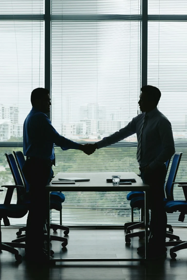 Silhouette of businessmen shaking hands in office. Symbolizing professional agreement and collaboration formats with business.