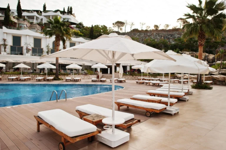 Luxury hotel swimming pool with sun loungers and umbrellas on a sunny day symbolizing digital marketing for tourism.