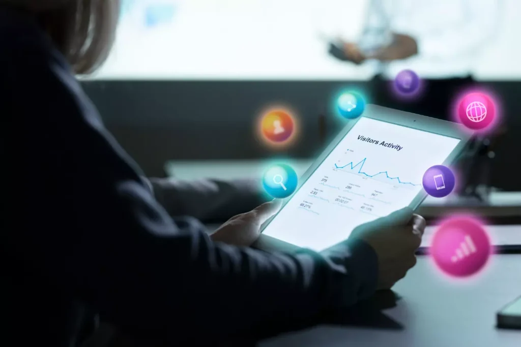 Tablet in the hands of the woman, on the monitor infographic and info about visitors activity. It about web analytics.